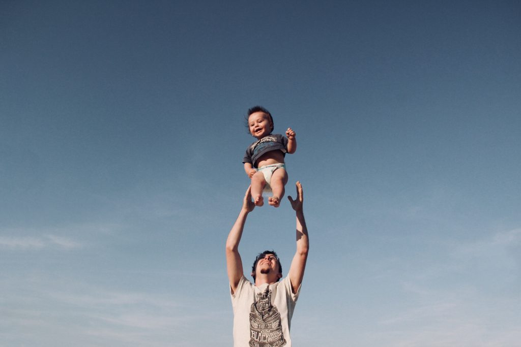 dad throwing toddler son up in the sky and catching him
